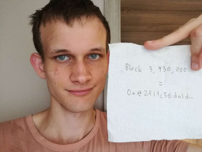 Vitalik Buterin, co-founder of Ethereum, holding up a handwritten note that reads "Block 3,930,000 = 0xe2f1fc56da1d..." representing an early Ethereum block hash.