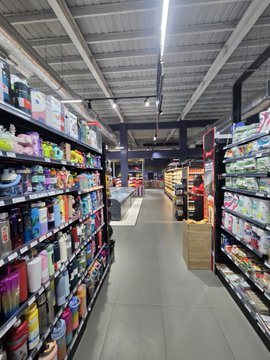 A wide aisle in a retail store with shelves stocked with various household goods and colorful products.