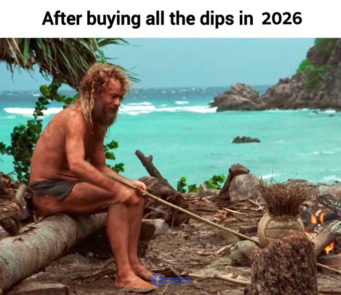 Captioned 'After buying all the dips in 2026,' the photo depicts a long-haired, bearded man in a primitive loincloth roasting something over a small fire on a tropical beach.