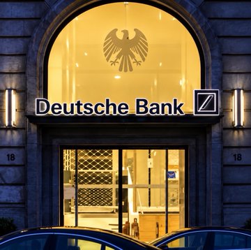 The illuminated facade of a Deutsche Bank branch displays its name and the iconic eagle emblem above the entrance, flanked by the number "18." This image of Germany's largest bank visually accompanies news of its imminent expansion into Bitcoin and Ethereum custody services, signaling traditional finance's deepening embrace of cryptocurrency.