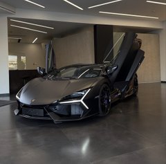 A matte black Lamborghini with scissor doors open is displayed in a sleek showroom, paired with the caption "New whip thanks Ethereum," implying the luxury sports car was purchased using profits or gains from the cryptocurrency Ethereum.