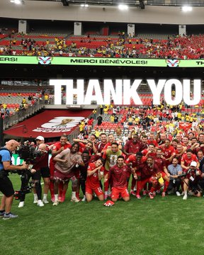 A jubilant sports team in red uniforms celebrates on the field at the Hang Seng Stadium, where a large "THANK YOU" banner is displayed on the scoreboard, capturing the post-victory excitement matching the "LFG!" sentiment.