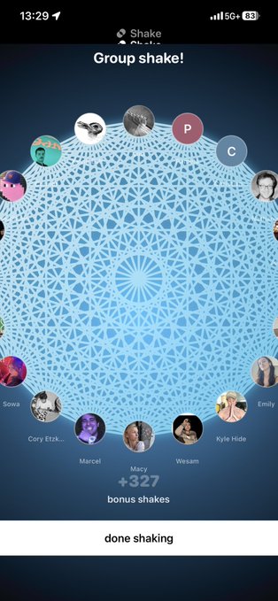 The image shows a phone screen with a group chat app open, displaying a blue circle filled with white circles containing various names of people participating in the chat. There are at least 13 different names visible within the circle. The text "Shake" is also present on the screen. The background color appears to be black and white, which contrasts with the blue circle and makes it stand out more prominently.