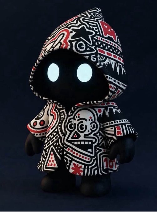 A small hooded figurine or mascot character wearing black and white patterned clothing with tribal-style red and white designs and glowing light-blue eyes.