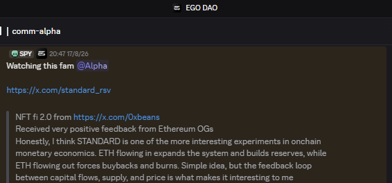 The image shows a Discord post in the #comm-alpha channel from the EGO DAO server, shared by user "spy" on 17/8/26, reading "Watching this fam @Alpha" with a link to standard_rsv. The post expresses regret at missing the $STANDARD token whitelist (WL) from the Standard project, which aligns with the image's "alpha" leak about $STANDARD and NFTfi 2.0 developments.
