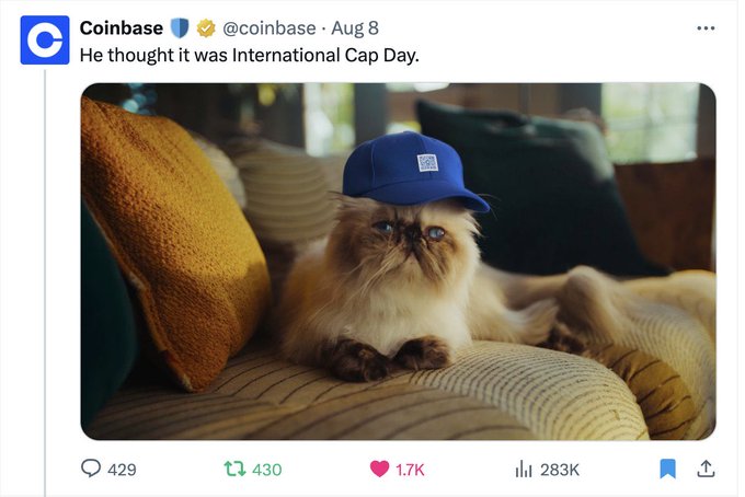 A Coinbase tweet from August 8 shows a grumpy-looking Himalayan cat wearing a blue cap, captioned "He thought it was International Cap Day," with the post gaining 283K views. The image ties into the accompanying commentary about @MrMigglesOnBase being positioned as crypto's premier cat mascot alongside Doge.
