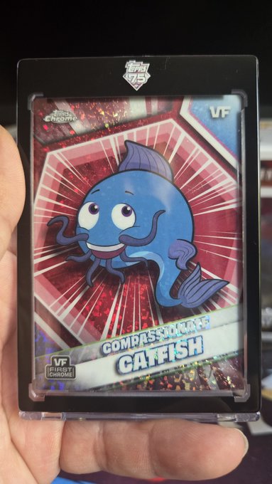 A hand holds up a Topps 'My Hero Academia' trading card featuring the character 'Compassionate Catfish', which has a 'VF First Chrome' designation.