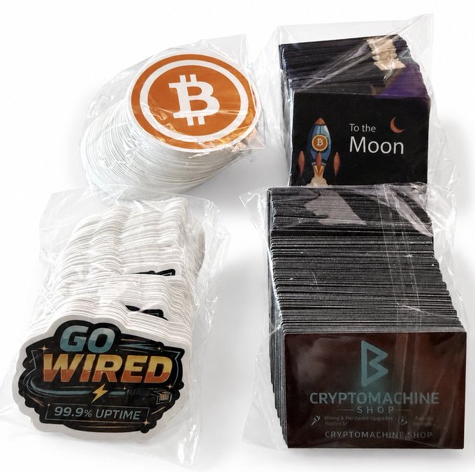 Four stacks of cryptocurrency-themed stickers—including Bitcoin (₿), "To the Moon" with a rocket, "Go Wired 99.9% Uptime," and CryptoMachine.Shop branded designs—are bundled in plastic packaging to restock the drawer, matching the post's announcement of returning to rotation.