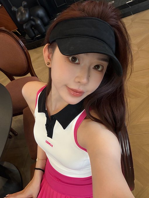 A young woman wearing a black visor and a white/pink ZOWEA tennis outfit takes a selfie in what appears to be a lounge or hotel lobby, with the ironic caption reflecting on missing a "golden dog" crypto pump while distracted by tennis. The ZOWEA branding on her polo contrasts comically with the post's lament about selling $7stonk too early.