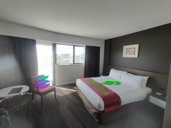 A modern hotel room features a bed with a red runner displaying the "Fast food" logo with a green checkmark, while a chair beside a small round table displays an overlaid Solana logo. The image humorously suggests the irony of a crypto maximalist being stuck in a hotel, as the Solana logo positioned on the chair seems isolated from the branded bed, mirroring how Solana maximalists may feel sidelined despite their loyalty.