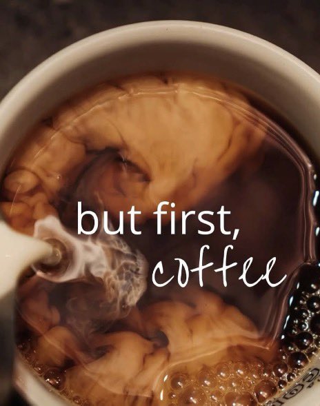 A close-up overhead shot of coffee in a white mug with cream swirling through it, overlaid with the text "but first, coffee".