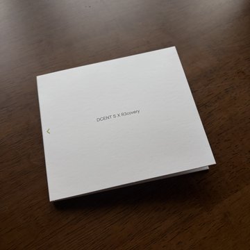A white box or envelope with the text 'SCENT S.X Recovery' printed on it, resting on a wooden surface.