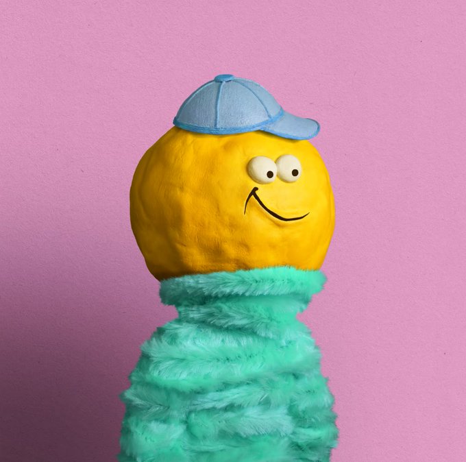 A yellow smiley face wearing a blue baseball cap sits atop a fluffy turquoise body against a pink background.