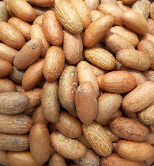 A close-up image of a pile of peanut shells or seed pods in various shades of tan and brown.