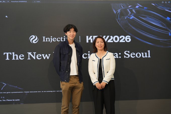 Two people pose in front of a large screen displaying "Injective | K[KEY]2026: Seoul" with the tagline "The New [Finan]cial [E]ra: Seoul," highlighting Injective's presence at the event. The image relates to the post by visually reinforcing Injective's deepening enterprise partnerships, including its collaboration with LG CNS, through branding tied to the Seoul-based K-KEY 2026 conference.