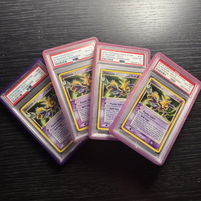 Four PSA-graded 2006 Pokémon Gold Star Alakazam-Holo cards (Gem Mint 10) from the EX Crystal Guardians set are fanned out on a dark wooden surface, with the caption referencing the recent $99,600 auction sale of a rare "spoon boys" Alakazam card.