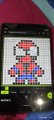 The image shows a smartphone displaying a pixel-art character resembling Mario rendered in a grid format, likely from the GLYPHS app. The post mentions an upcoming final upload for GLYPHS with a mint arriving in a few hours, suggesting this pixel artwork is a preview or sample of the character's design before the official NFT mint.