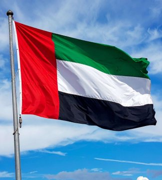 The flag of the United Arab Emirates flies against a blue sky, symbolizing the Abu Dhabi sovereign wealth funds' significant $763M+ investment in BlackRock's Bitcoin ETF, with Mubadala ($490M) and the Abu Dhabi Investment Council ($273M) driving growing institutional adoption of Bitcoin.