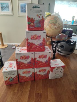 A pyramid stack of "Grumps" NFT collectible boxes with a "goblintown" branded box on top, displayed on a wooden table. The image showcases the physical merchandise tied to the Goblintown NFT collection, complementing the post's excitement about receiving the "Grumps" collectibles with impressive quality.
