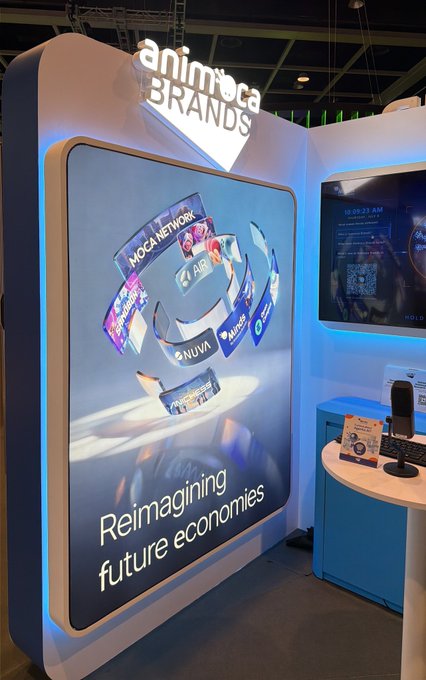 An Animoca Brands trade show booth features a large display with the tagline "Reimagining future economies" and showcases brands including Moca Network, AIR, NUVA, and Animes.