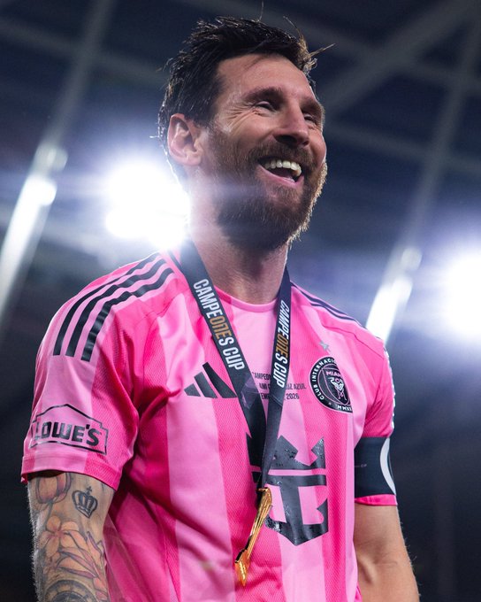 Soccer player Lionel Messi smiles while wearing a pink Inter Miami CF jersey with 'Lowe's' sponsor and a Leagues Cup medal around his neck.