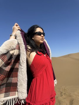 iced tea with a straw, white and red plaid blanket, and sunglasses on the woman's face are present in the desert landscape.