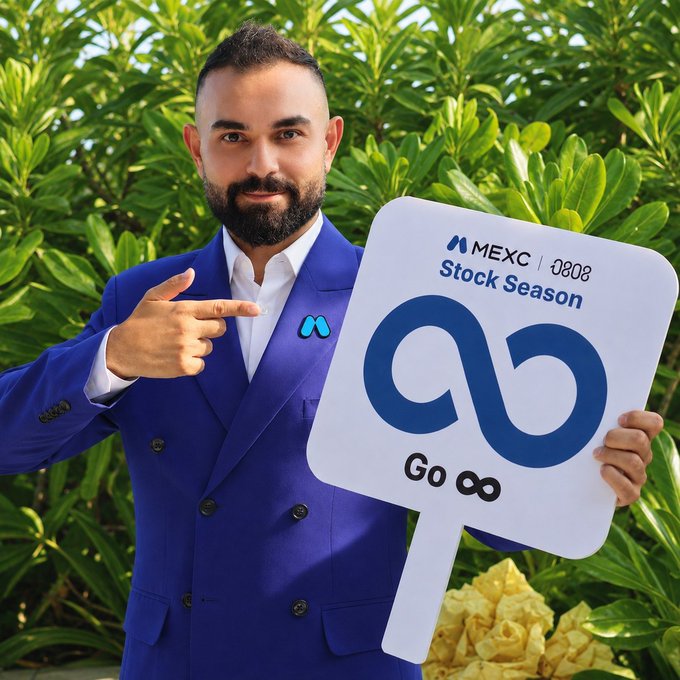 A man with a beard, wearing a blue suit, points to a white sign reading "MEXC Stock Season" with "Go" and an infinity symbol below, set against lush green foliage — visually promoting MEXC's 0 Fee Stock Season campaign that unifies Stock Futures, Tokenized Stocks, and RealStocks trading in one place.