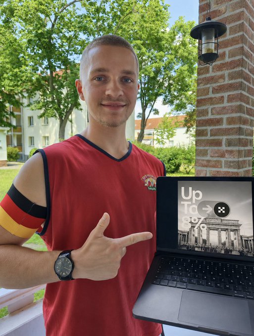 A man in a red Germany jersey with a black, red, and gold armband points toward a laptop screen displaying "Up To 8%" alongside an image of the Brandenburg Gate, promoting OKX's regulated exchange status ahead of the July 1 MiCA deadline.