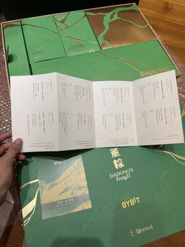 The image features an open gift box from Bybit, which contains a green card with gold lettering that reads "Bybit Dragon Boat Festival" and "B&T". The box also includes a menu card for the Dragon Boat Festival, suggesting that the contents are related to this event. The post about the gift box was written by @BybitMartin, who has tagged the image with the hashtag #BybitZH.