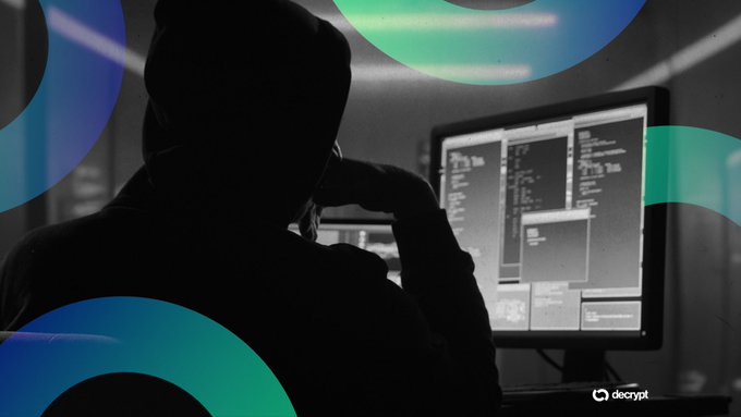 A silhouetted figure wearing a beanie sits at a desk looking at code on multiple monitors, with a 'decrypt' logo in the corner and abstract blue and green circle graphics overlaid on the image.
