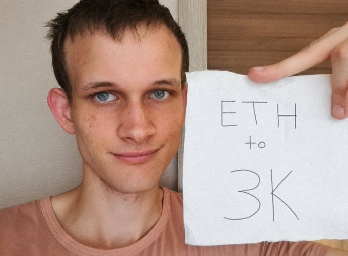 A young man smiles while holding up a handwritten note that reads 'ETH to 3K', referencing the cryptocurrency Ethereum's price target.