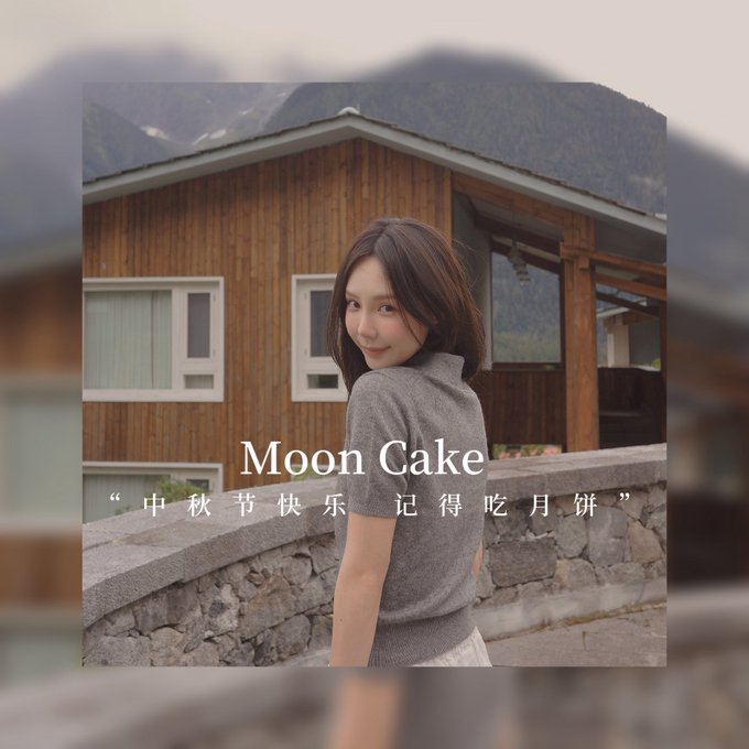 Photo of a woman in a gray sweater standing in front of a wooden cabin with mountains in the background, captioned 'Moon Cake' with Chinese text '中秋节快乐 记得吃月饼' (Happy Mid-Autumn Festival, remember to eat mooncakes).