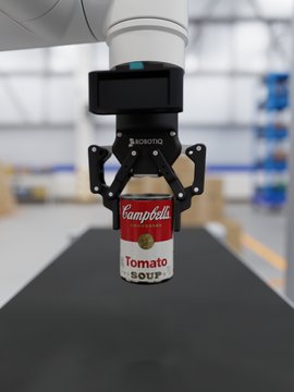 A robotic gripper arm holding a can of Campbell's Tomato Soup in an industrial setting.