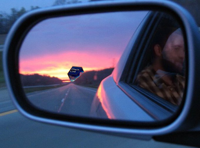 A side mirror reflects a highway at sunset, capturing a driver's profile and a blue hexagonal graphic labeled "Chain Link" floating in the distance, visually representing the "$Link" text from the post.