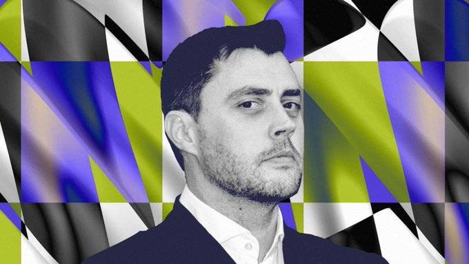 A stylized portrait of a bearded man in a suit against a checkered background of black, white, blue, and yellow geometric patterns.