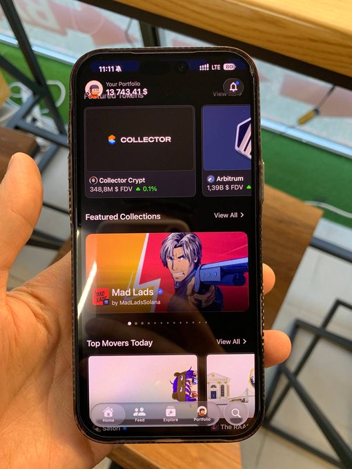 A hand holds a smartphone displaying a Web3 portfolio app (likely Magic Eden) showing '13,743.41$' in total portfolio value, with featured collections including 'Mad Lads' by MadLadsSolana.