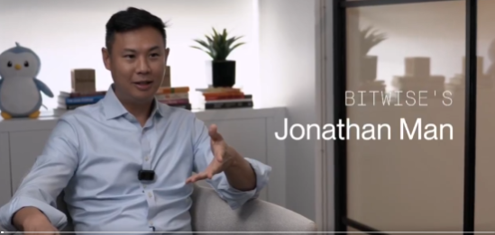 A video screenshot showing a man in a light blue shirt speaking in an office setting, with text overlay reading 'BITWISE'S Jonathan Man'.