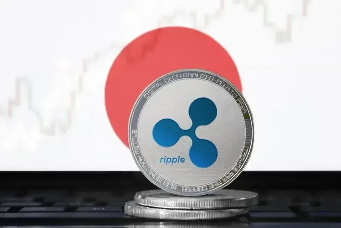A physical Ripple (XRP) cryptocurrency coin resting on a laptop keyboard with the Japanese flag in the background.