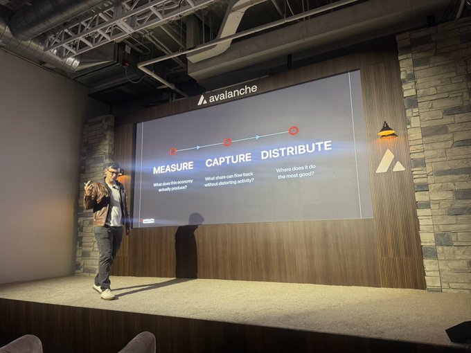 A man presents on stage in front of a large screen displaying the Avalanche logo and a process diagram reading 'MEASURE - CAPTURE - DISTRIBUTE' with explanatory questions about economy and flow.