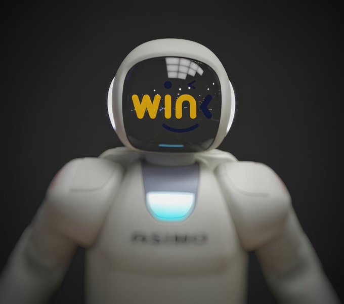 A small white robot with a digital face screen displaying the word 'win' in yellow letters, photographed against a black background.