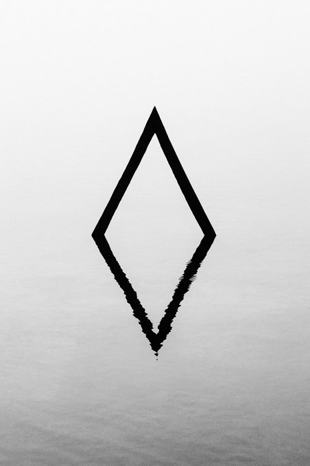 A minimalist black ink drawing of a diamond or rhombus shape on a white, slightly textured background.