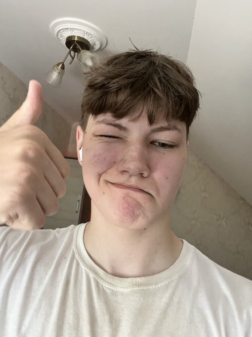 A young person winks and gives a thumbs-up in a selfie, wearing a white t-shirt and a wireless earbud, in front of a ceiling with light fixtures.

This image directly relates to the "day 87 of posting selfie until $PENGU hits $1" post, serving as the selfie for that day and supporting the message that the streak of daily selfies correlates with positive price movement (+2.3%).