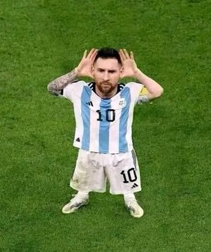 An overhead shot of soccer player Lionel Messi wearing an Argentina #10 jersey on a green field, posing with both hands near his ears.