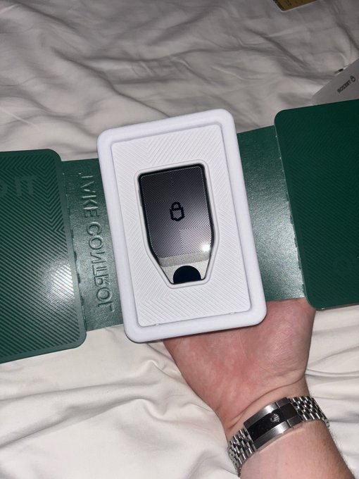 A person holds a Trezor hardware cryptocurrency wallet in its white box packaging, with the text 'YOUR CRYPTO. LIKE GOV/1501.' visible on the green flap.