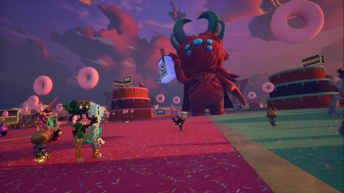 A screenshot from a video game featuring a large red horned monster holding a hammer in a whimsical landscape with pink donut-shaped clouds, donut decorations, and small cartoon figures on a pink sprinkled ground.