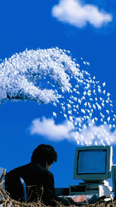 A surreal digital art image shows a person sitting at an old CRT computer, with the screen emitting a flock of white birds that fly across a bright blue sky.