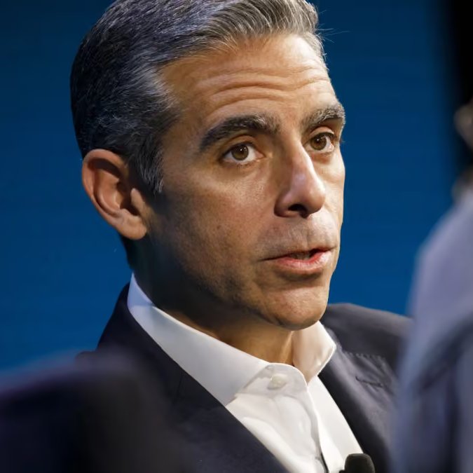 A close-up of David Schwartz, Coinbase’s chief legal officer, speaking at a press event against a blue backdrop.