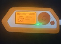 A yellow and white electronic device labeled 'NEMESIS X WIFI' with an orange antenna and a green LED indicator light glowing in the center.