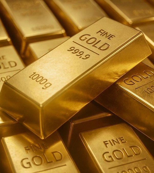 A close-up of stacked gold bars stamped with 'FINE GOLD 999.9 1000g', showcasing their polished, reflective surfaces.