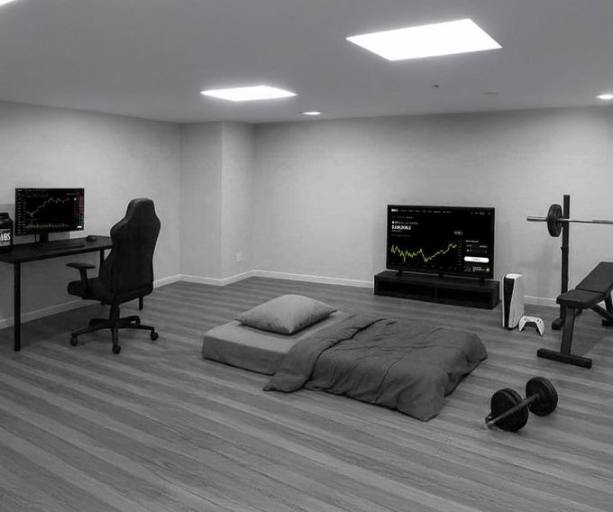 A modern, minimalist bedroom setup in black and white includes a gaming chair, dual monitors showing financial charts (Ethereum/EUR charts), a mattress on the floor, and workout equipment.